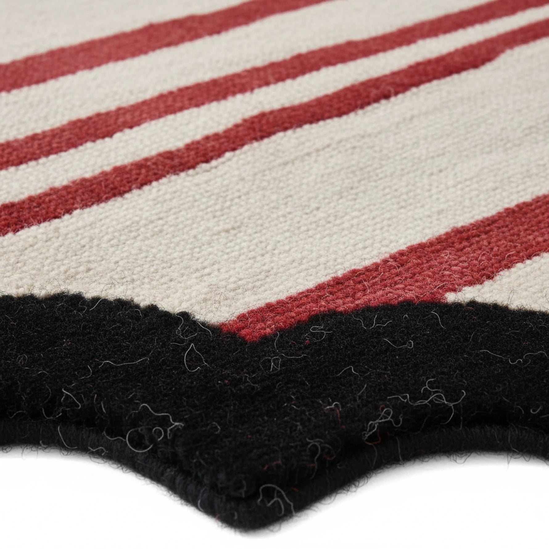 Close-up of a striped rug with red, white, and black colors.