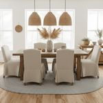 Dining room with wooden table and beige chairs, large windows, gray jute rug, and decorative elements.