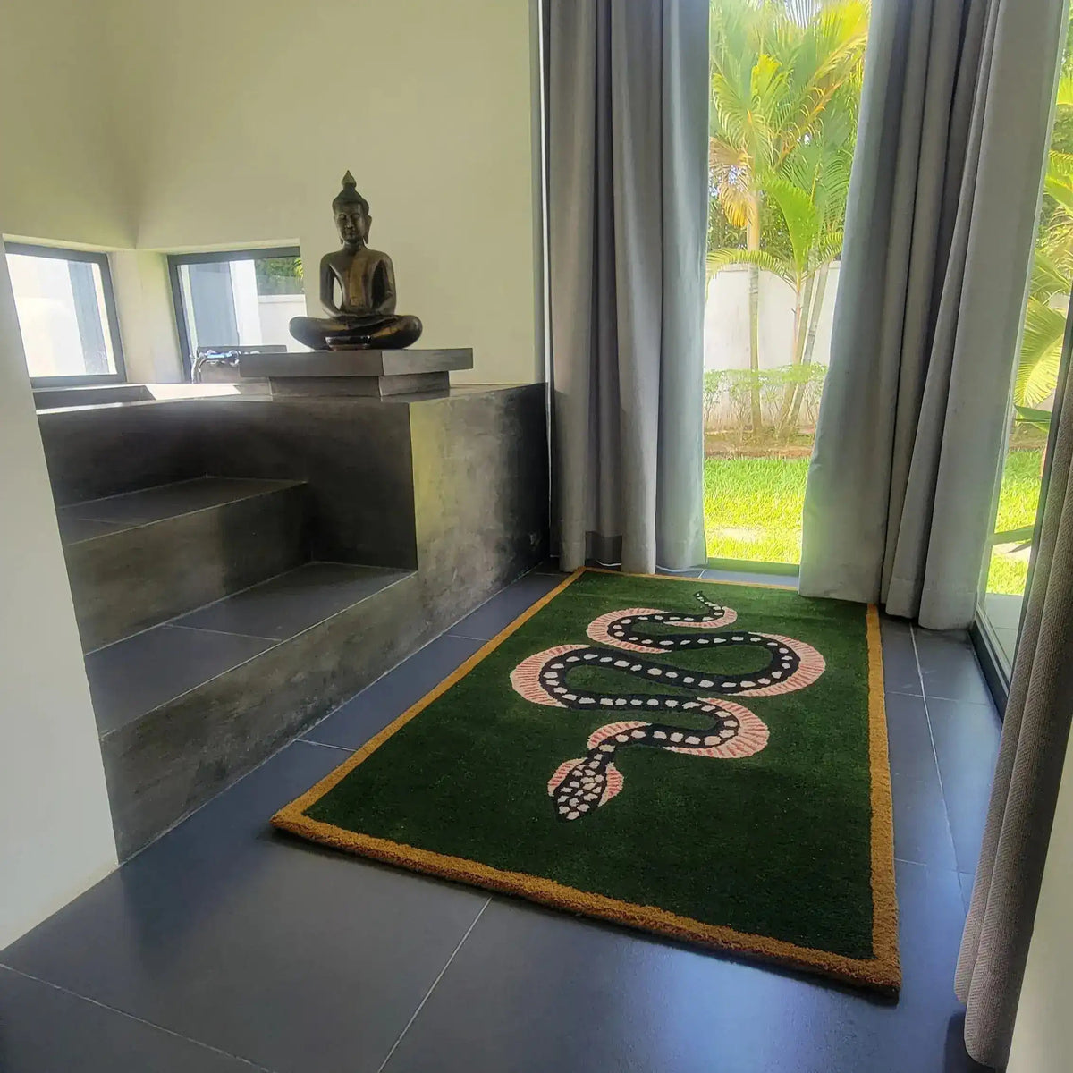 A stylish Green and Black Snake Hand Tufted Wool Area Rug placed in a modern room with large windows and a serene statue. This vintage rug adds a touch of elegance, perfect for a dining room or living room setting. Its wool texture and unique design make it an ideal dining table rug or living room rug, sized 8x10, bringing warmth and character to the space.