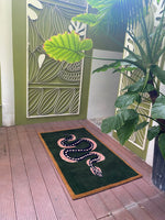 A stylish Green and Black Snake Hand Tufted Wool Area Rug laid on a wooden deck. This vintage rug features an elegant snake design, making it a perfect addition to dining rooms or as a dining table rug. Ideal for living room settings, this 8x10 wool rug adds a touch of sophistication and warmth to any space.
