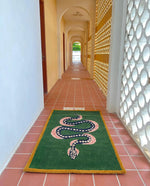 A vibrant Green and Black Snake Hand Tufted Wool Area Rug displayed in a well-lit hallway with terracotta tiles. This vintage rug features an intricate snake design, perfect for adding a unique touch to a dining room or living room. Ideal as a dining table rug or as part of living room rugs 8x10 collection, this wool rug combines style and functionality.