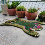 A vibrant Green Asian Tiger Wool Rug displayed on a patio, surrounded by potted plants. This unique area rug features a colorful abstract tiger design, perfect for adding a vintage touch to dining rooms, offices, and formal spaces. Its wool texture makes it a cozy addition to any dining room carpet collection.