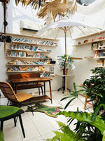 A cozy reading nook featuring a Green Asian Tiger Wool Rug on the floor, adding a touch of vintage charm. The area rug enhances the space with its abstract tiger design, ideal for dining rooms, offices, or as a formal dining room rug. Surrounded by bookshelves and lush plants, this wool rug introduces warmth and elegance, perfect for dining room carpets.
