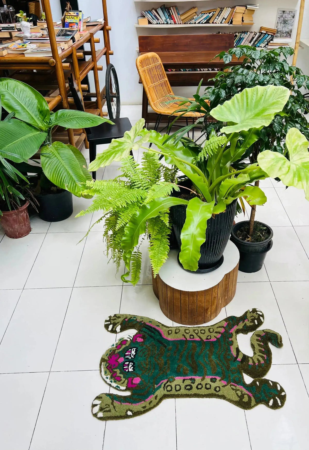 A vibrant and unique Green Asian Tiger wool rug in an office setting, surrounded by lush green plants. This vintage rug adds a touch of character and charm to the room, making it an ideal piece for dining room carpets or formal dining room rugs. The area rug features an abstract tiger design, perfect for enhancing the aesthetic of any dining room or office space.