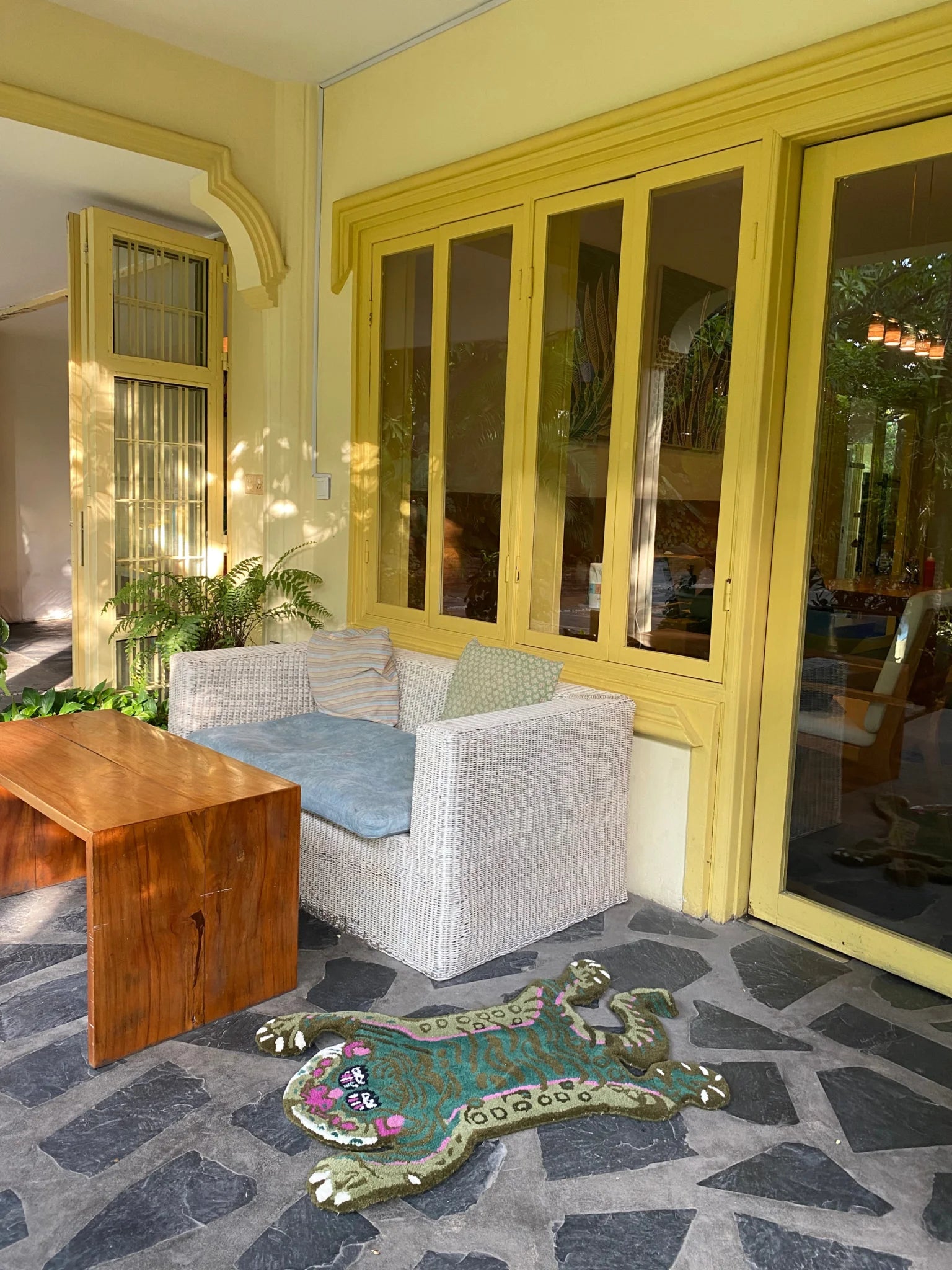 Stylish Green Asian Tiger Wool Rug adorning a modern patio with a wicker armchair and wooden table. This vintage area rug adds a touch of elegance, perfect for a dining room or office, blending seamlessly as a formal dining room rug or dining room carpet.