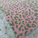 Pink rug with green abstract pattern on a concrete floor