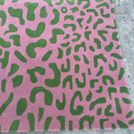 Pink fabric with green abstract pattern on a concrete surface