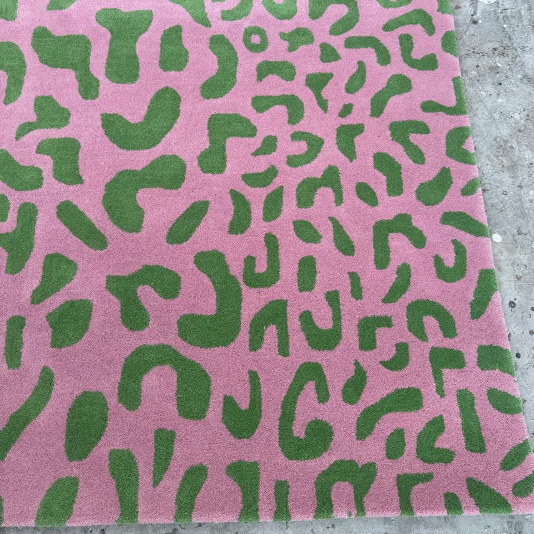 Pink fabric with green abstract pattern on a concrete surface