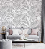 Grey Tropical Foliage Wallpaper of white ferns on grey behind a grey sofa with pink cushions