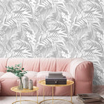 Grey Tropical Foliage Wallpaper of white leaves on grey behind a soft pink sofa