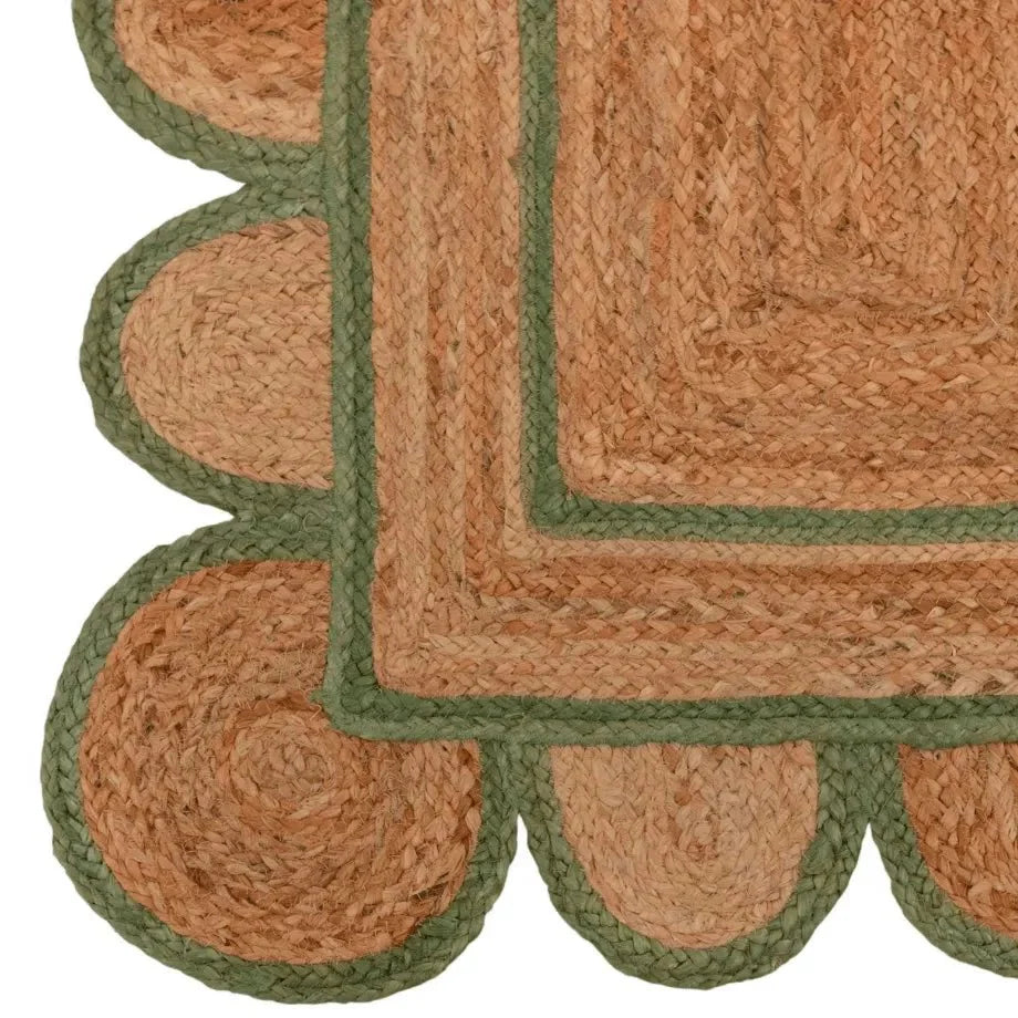 A handmade jute rug with an olive green scalloped border on a white background.