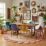 Dining room with a wooden table and colorful chairs on a patterned scalloped jute rug.
