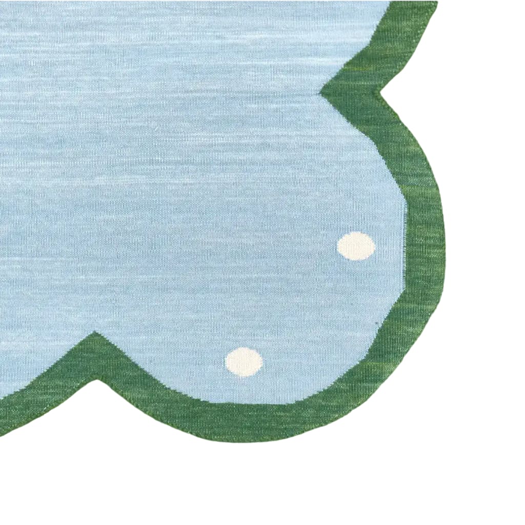 Close-up of a light blue cotton area rug with scalloped edges and dotted design, perfect for adding a boho touch to your dining room or bedroom.