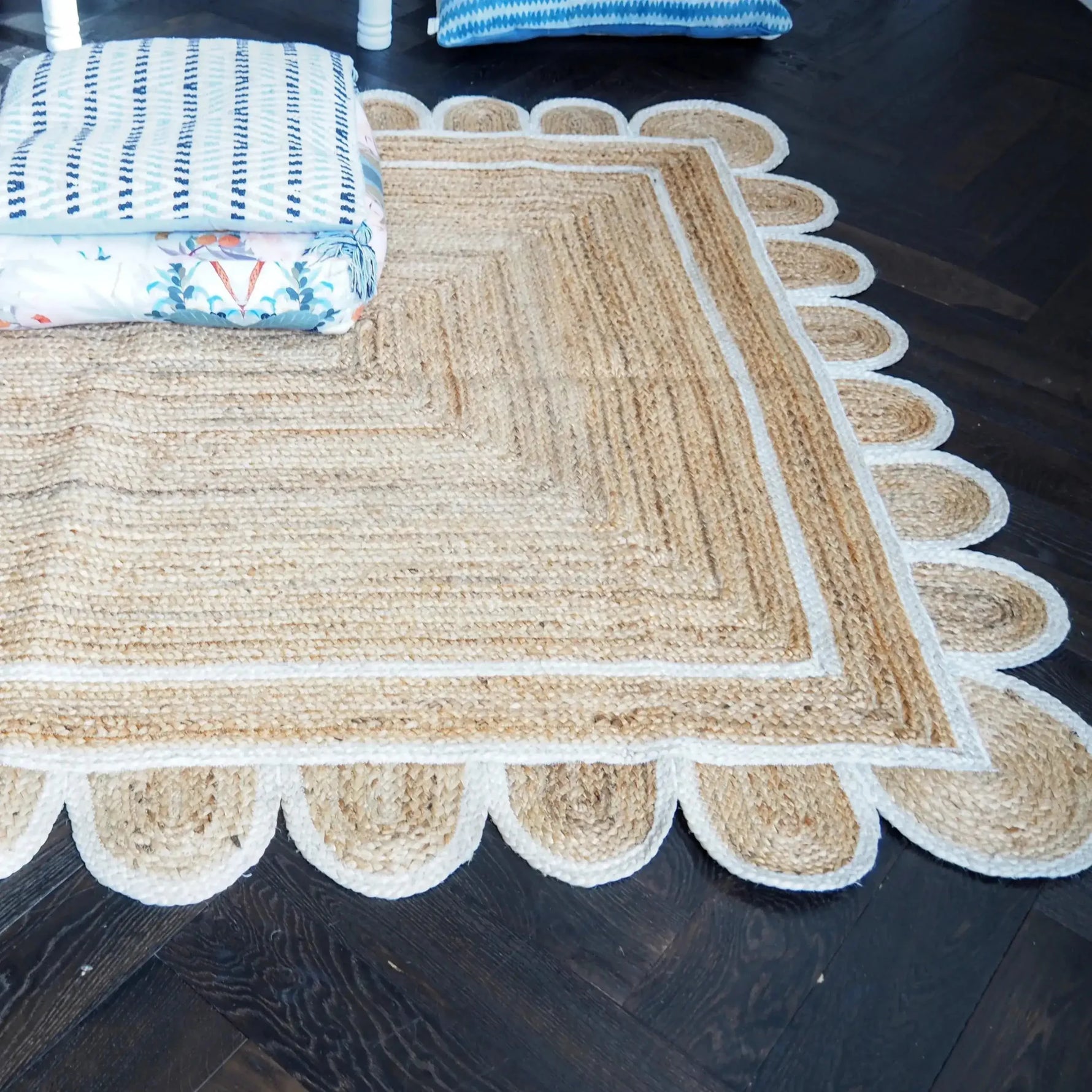 This image showcases a beautiful handmade white scalloped jute area rug, perfect for adding a touch of elegance to your dining room or living room. The rug's intricate scalloped edges and natural jute texture make it an ideal choice for those seeking stylish and durable rugs for living room spaces.