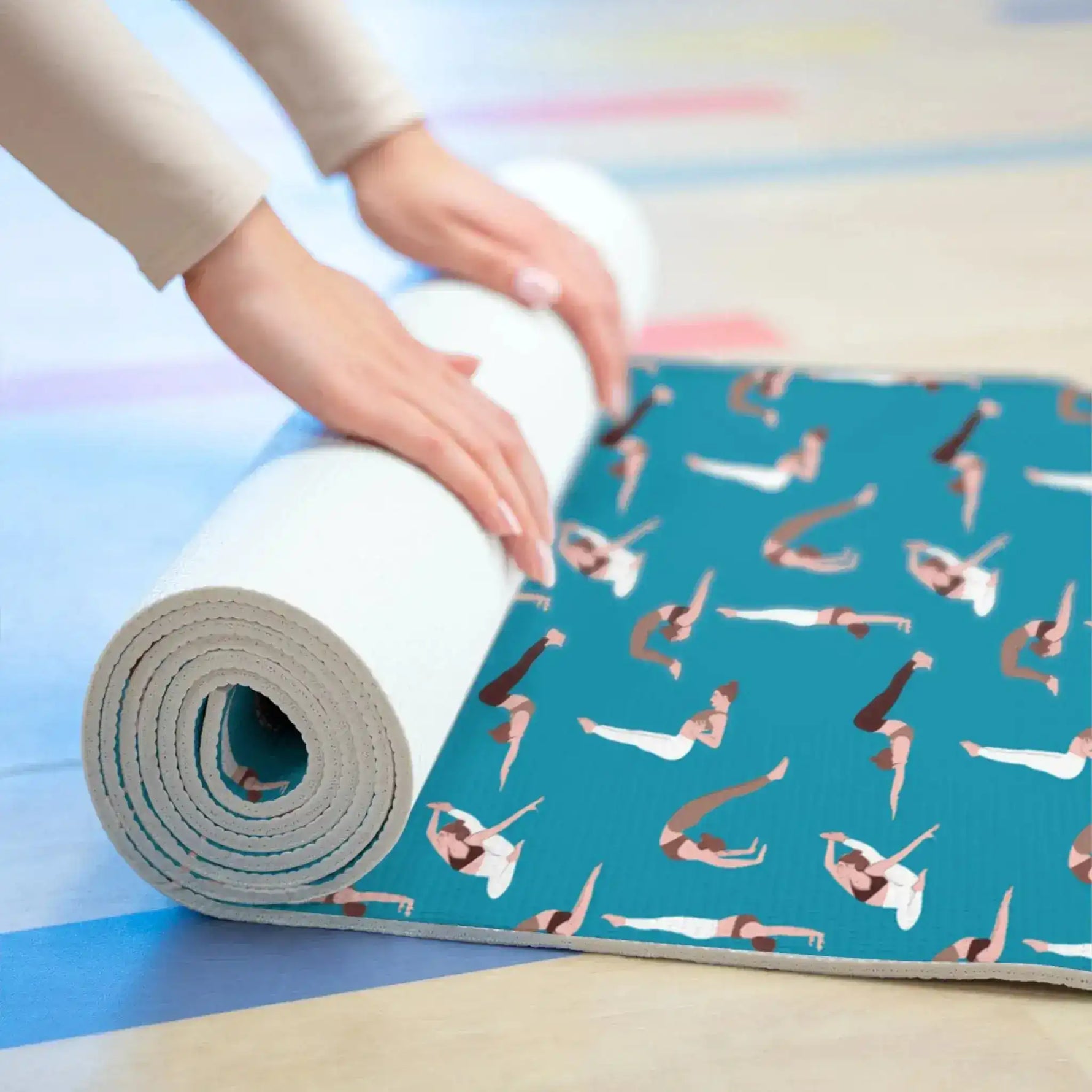 Hands rolling up the teal pose-print yoga mat, showing the foam edge