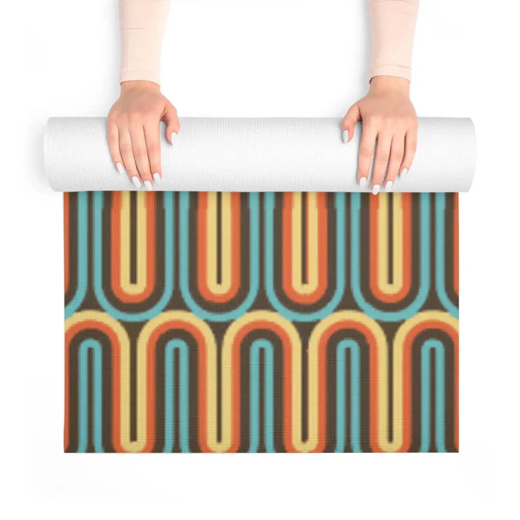 Hands unrolling a yoga mat with retro looping lines in teal, orange and cream on brown