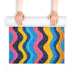 Hands unrolling Carnival Currents yoga mat revealing wavy confetti-dotted stripes in bright colors