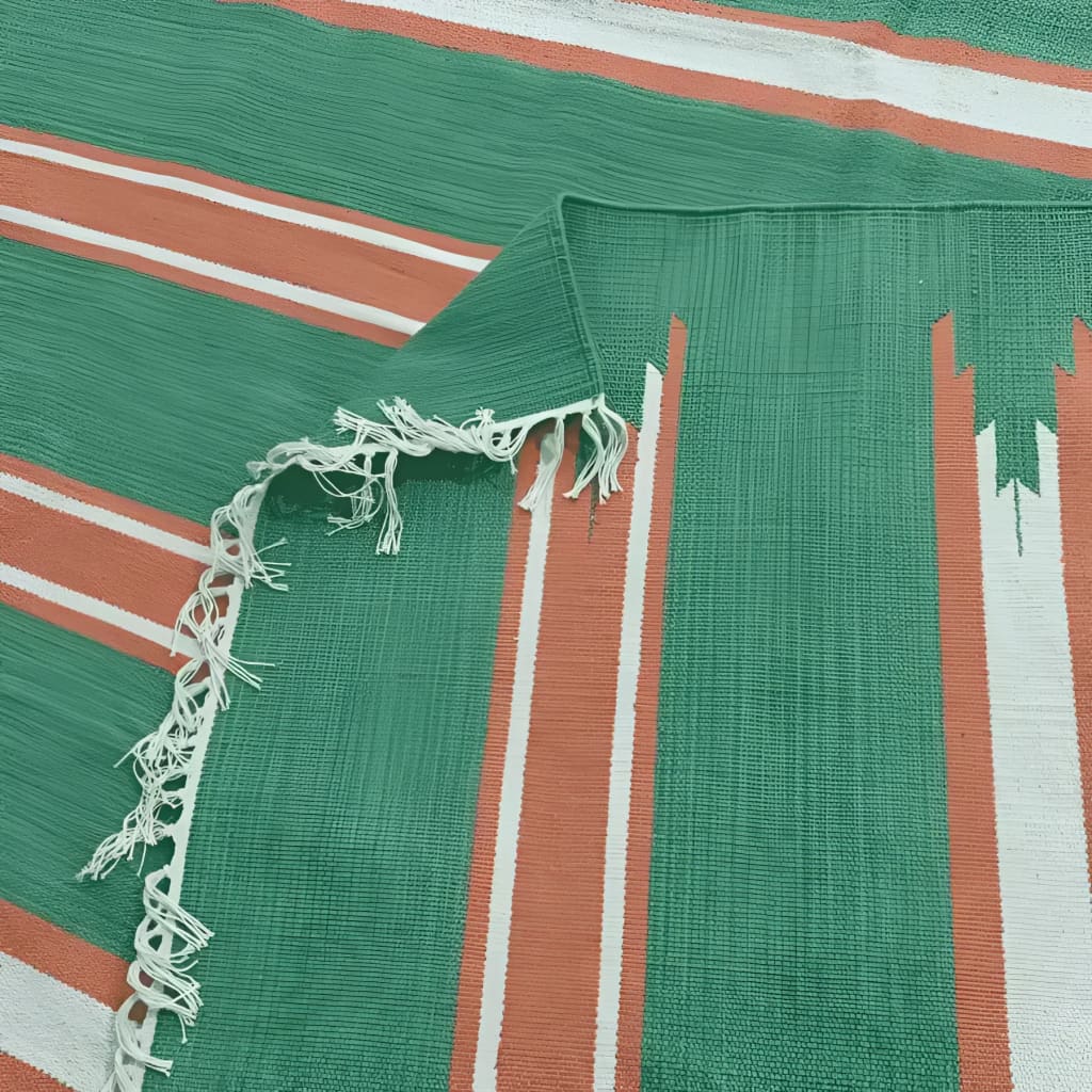 Close-up of a handwoven green and red stripe cotton area rug with fringes, perfect for adding a boho touch to dining rooms or living rooms. Ideal as a formal dining room rug or a cozy addition to any space.