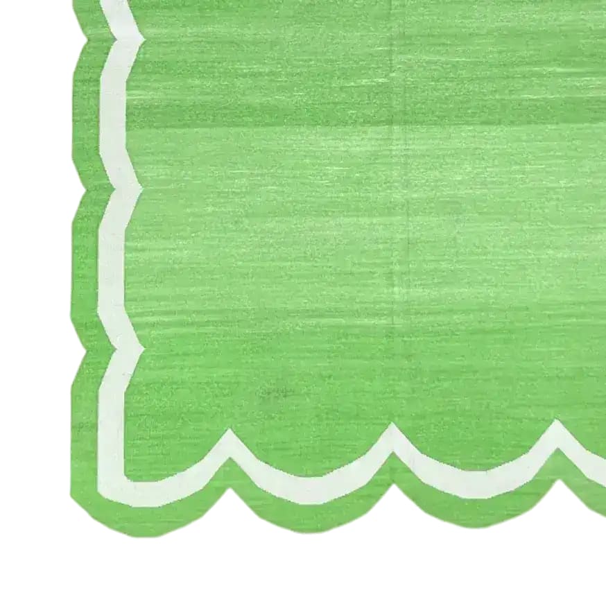 A close-up view of a handwoven green and white scallop cotton area rug, perfect for adding a boho touch to your living room. This large area rug features a unique scalloped edge design, ideal for those seeking stylish and comfortable rugs for living room spaces.