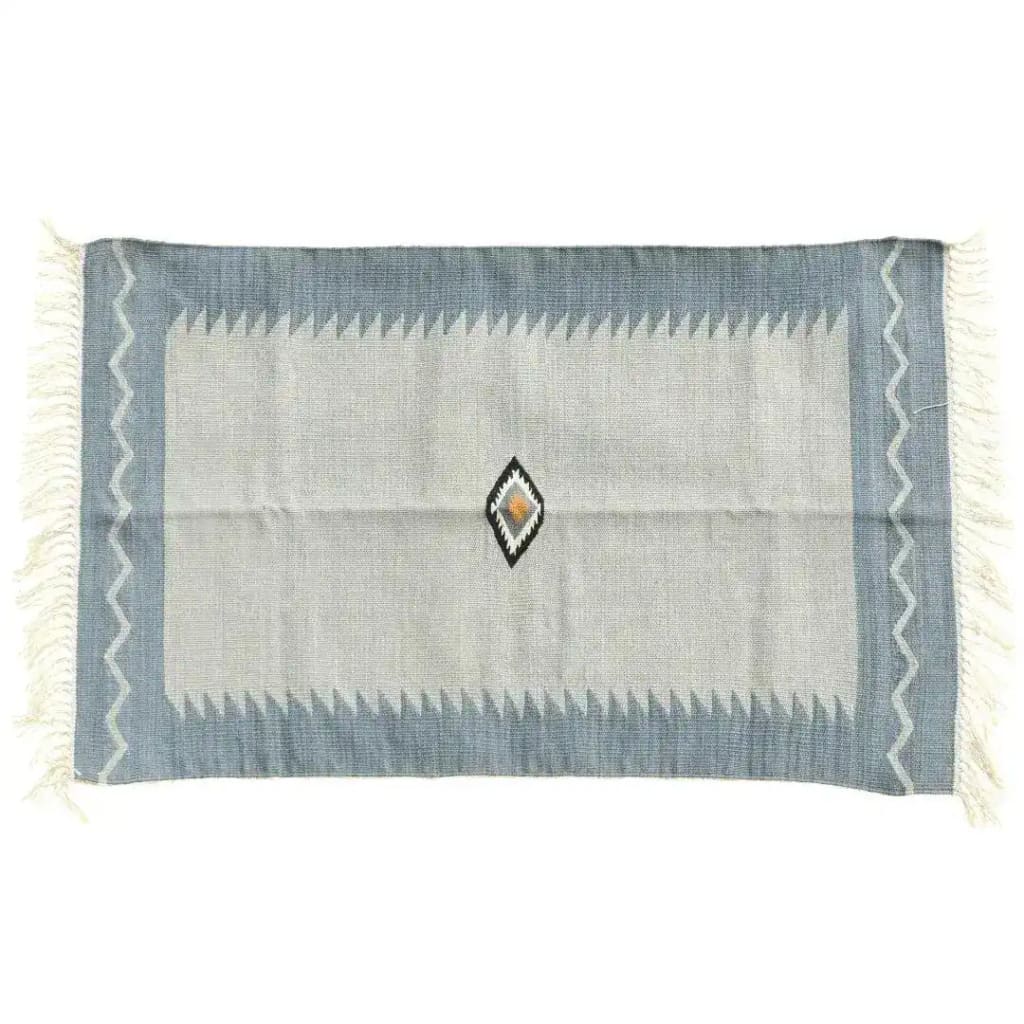 Handwoven minimalistic vintage gray cotton area rug with fringes, ideal for a boho-themed bedroom. The rug features a central diamond pattern in subtle hues, bordered by a soft gray with intricate zigzag edges. This large area rug adds a touch of elegance and warmth to any bedroom decor.