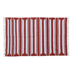 A handwoven red and white cotton area rug with accent stripes, perfect for enhancing living room and dining room spaces. This large boho rug features fringed edges, adding a stylish touch under a dining table.