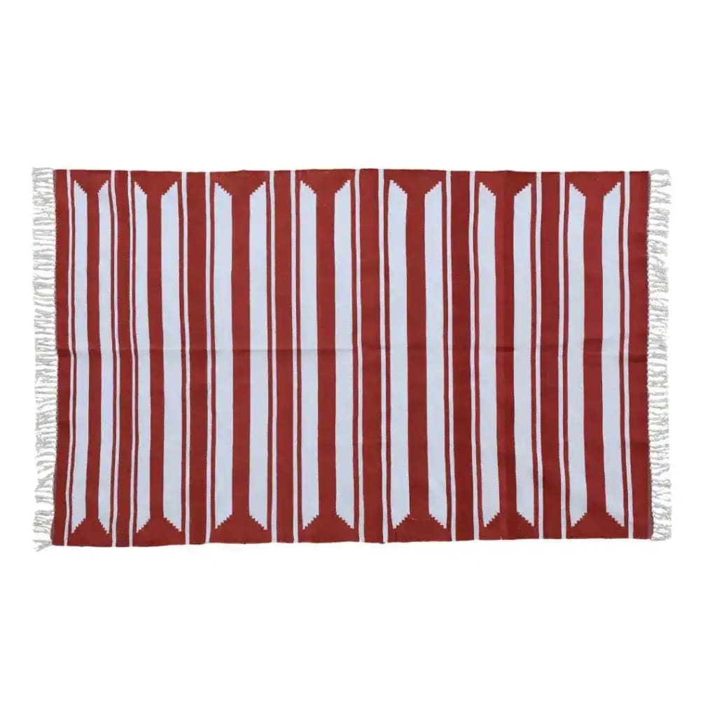 A handwoven red and white cotton area rug with accent stripes, perfect for enhancing living room and dining room spaces. This large boho rug features fringed edges, adding a stylish touch under a dining table.