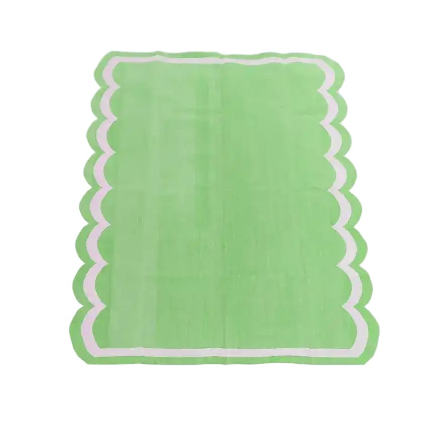 This is a vibrant green handwoven reversible cotton area rug with a unique scalloped edge, perfect for adding a boho touch to your dining room or living room. Ideal as an 8x10 living room rug or as a chic dining room carpet.