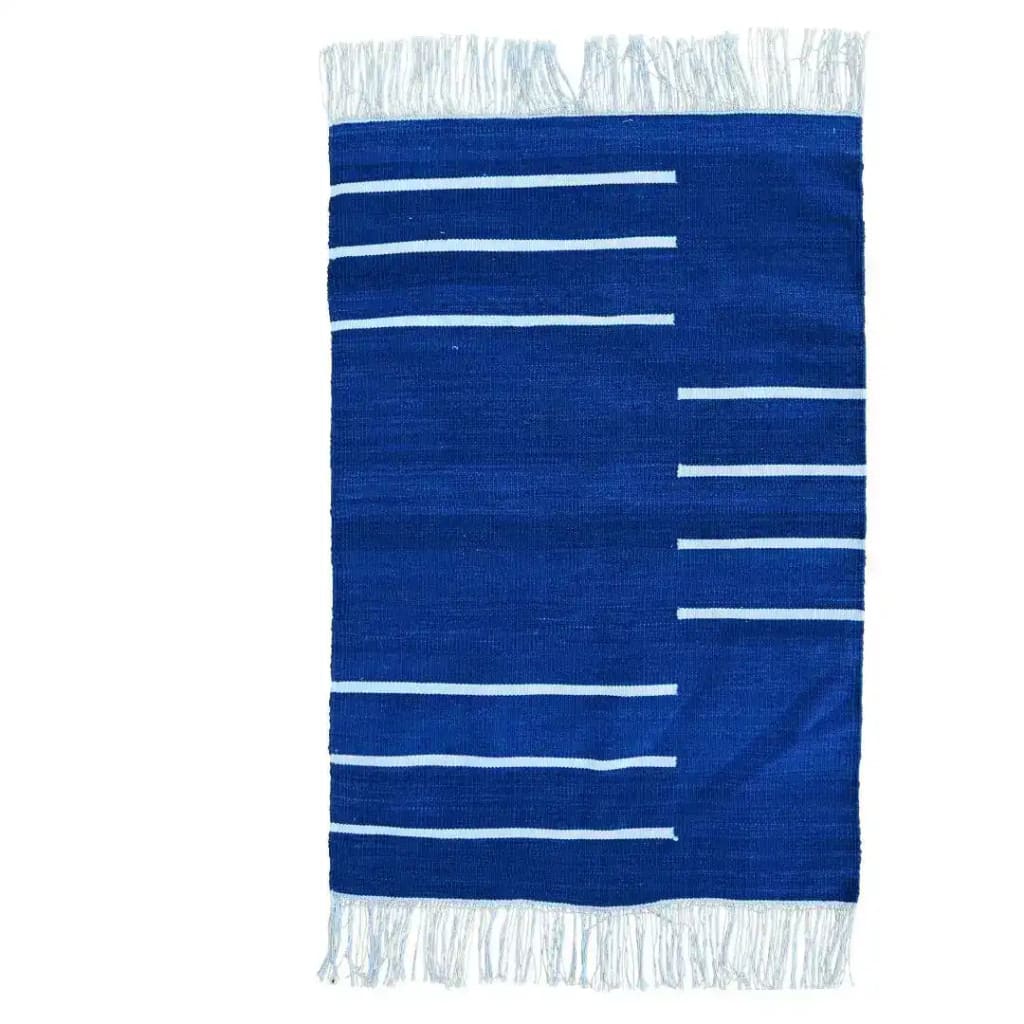 A handwoven royal blue and white minimalistic cotton area rug featuring a simple striped pattern and fringed edges. Ideal for adding a touch of elegance to a dining room or office, this boho rug combines style with the comfort of cotton, making it a perfect choice for rugs in an office setting.