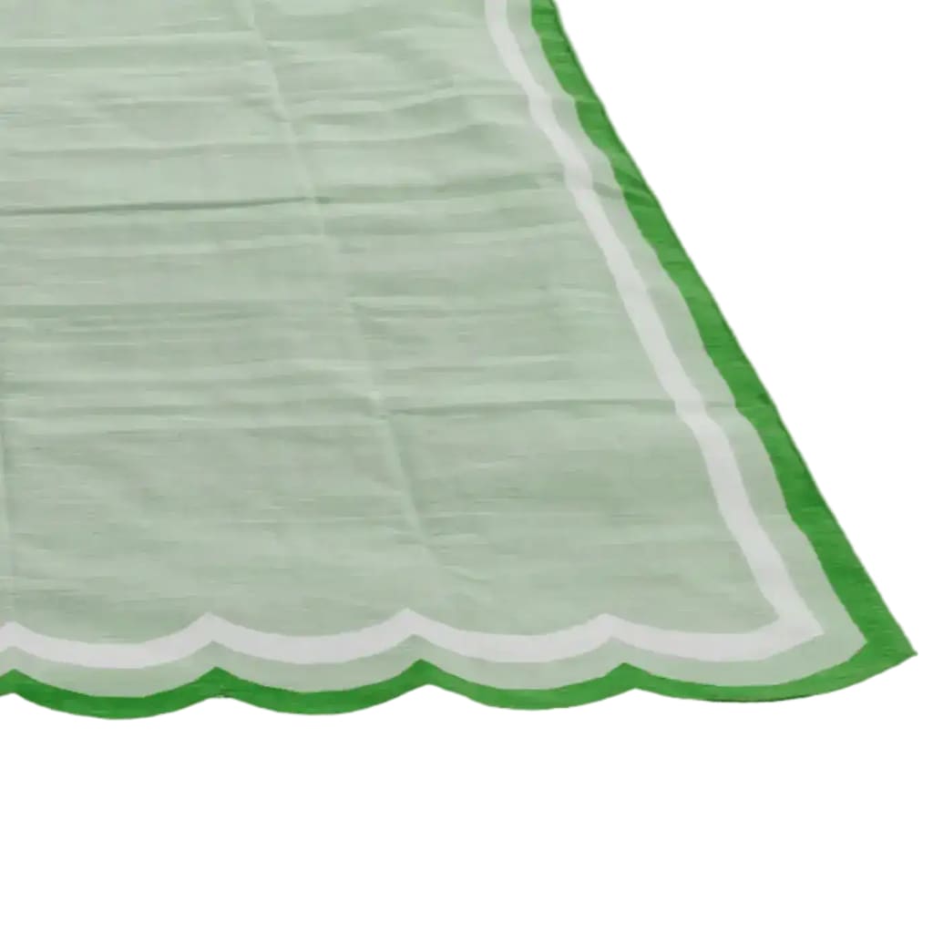 A beautifully handwoven scalloped cotton area rug in light green, perfect for adding a vintage touch to your living room or bedroom. The rug features a unique scalloped edge with a vibrant green border, ideal for boho-inspired decor. This versatile cotton rug is an excellent choice for living room rugs 8x10, offering both style and comfort.