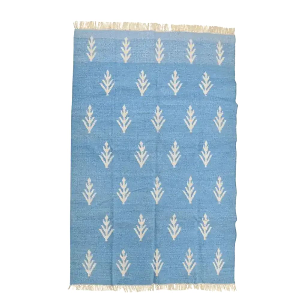 Top view of a handwoven white floral blue cotton area rug with fringes, ideal for large living rooms. This boho rug features a soft blue background adorned with elegant white floral patterns, perfect for adding a touch of style to your living space. Its cotton material ensures durability and comfort, making it a great choice for those seeking large area rugs for their living room.