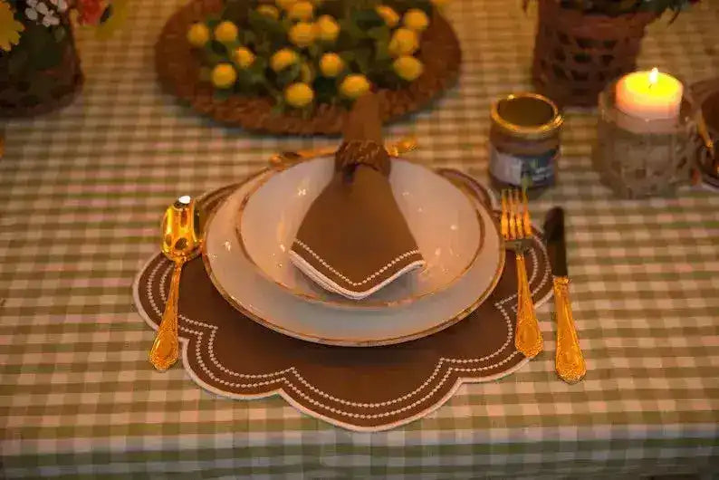 Hazelnut Haven Placemats brown scalloped place setting with gold cutlery candlelight and yellow flower centerpiece on gingham