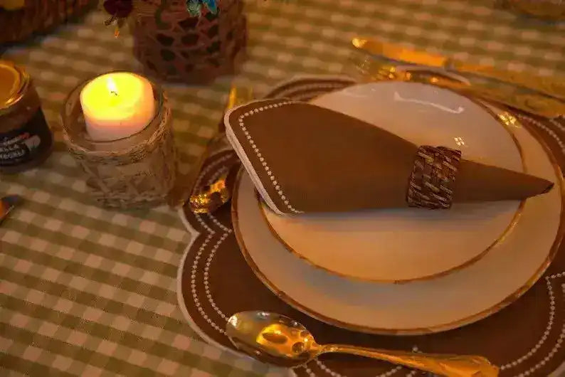 Hazelnut Haven Placemats brown scalloped with woven napkin ring and lit pillar candle in amber candlelit table setting