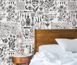 Herbal alchemy wallpaper detail with botanical drawings, candles and script behind a wood-framed bed