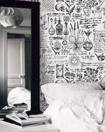 Herbal alchemy wallpaper with inky botanical sketches and script beside a bed and tall mirror
