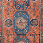 The Heritage Bloom Hand Knotted Rug showcases a stunning blend of vibrant blue and orange hues, featuring intricate floral patterns typical of vintage Persian rugs. Perfect for those seeking large living room area rugs, this piece adds a timeless elegance and warmth to any space.