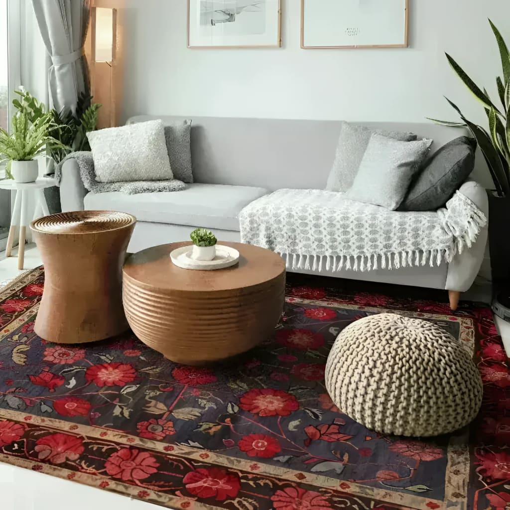 A cozy living room featuring a Heritage Chic Hand Knotted Area Rug with a vintage Persian design. The floral rug showcases rich red and navy hues, adding a touch of elegance to the modern setting. Perfect for rugs for living room setups, the rug complements a gray sofa and wooden coffee tables.
