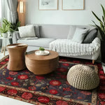 A cozy living room featuring a Heritage Chic Hand Knotted Area Rug with a vintage Persian design. The floral rug showcases rich red and navy hues, adding a touch of elegance to the modern setting. Perfect for rugs for living room setups, the rug complements a gray sofa and wooden coffee tables.