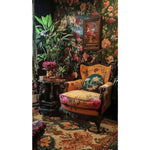 A luxurious living room showcasing a Heritage of Persia Wool Hand Knotted Area Rug. The rug features intricate floral patterns in rich colors, complementing the ornate armchair and floral wallpaper. Ideal for large living rooms or offices, this wool rug adds elegance and warmth to any space.