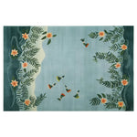 The Humming Haven Knotted Wool Rug, a large area rug perfect for living rooms, features a serene design with hummingbirds and floral patterns on a soft blue background, creating a tranquil atmosphere.