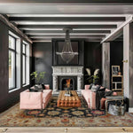 Living room with pink sofas, a fireplace, and decorative black floral handmade rug.