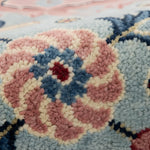 Close-up of a textured rug with pink, blue, and beige colors.