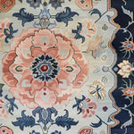Close-up of the Imperial Blossom Medley Hand Tufted Rug showcasing its intricate floral design in soft pink, blue, and beige hues. Perfect as an area rug for living rooms or offices, this vintage-style wool rug adds an elegant touch with its detailed patterns and vibrant border.