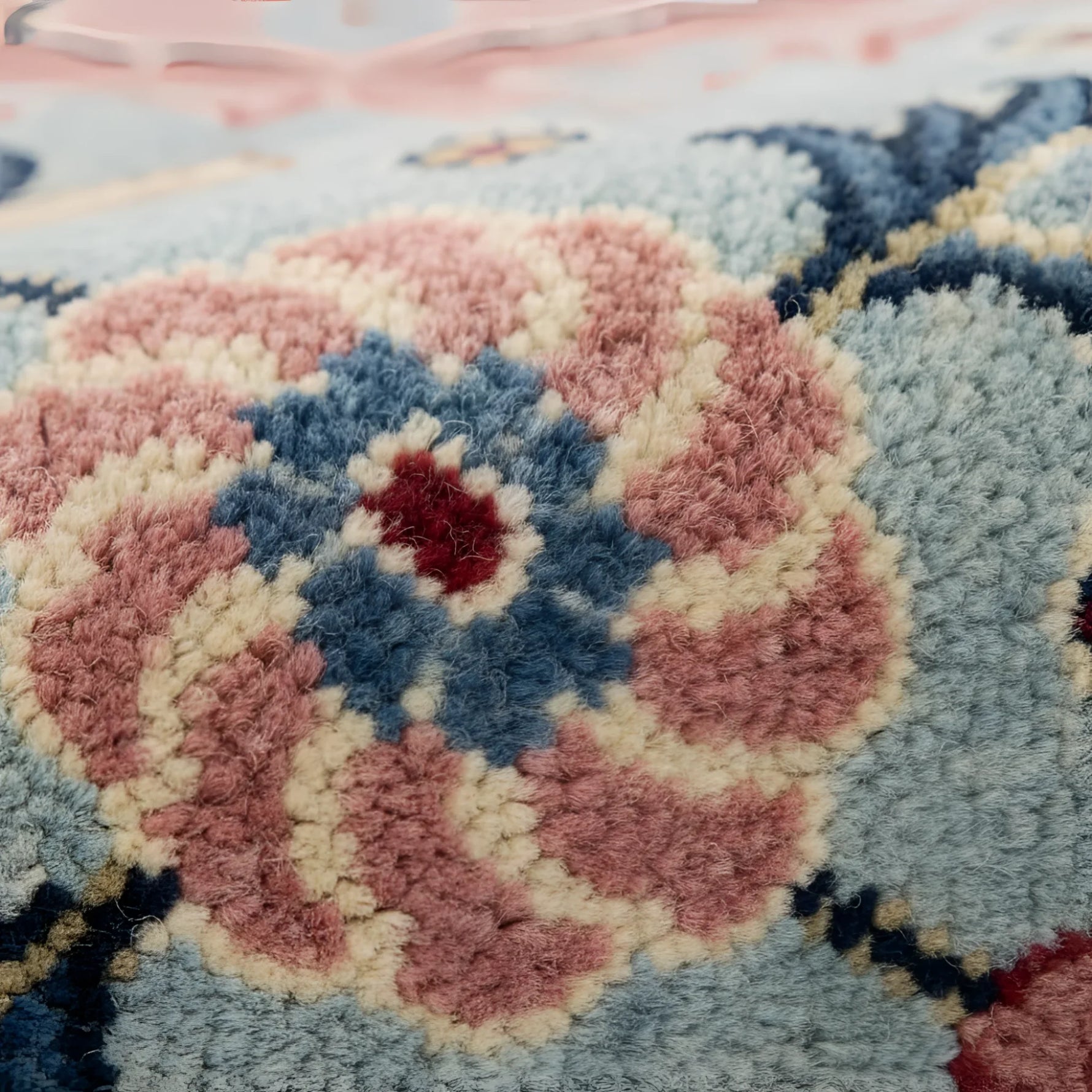 Close-up of a textured rug with pink, blue, and beige colors.