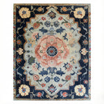 Traditional hand-tufted rug with a navy border, sage field, and a large pink floral medallion in classic Persian style