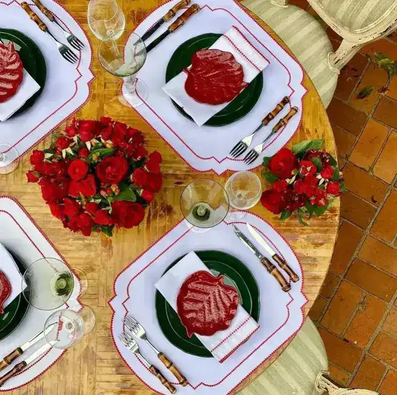 Imperial Crimson Placemats four-place table overhead — white mats with crimson bead-dot border, green plates and red flower decor