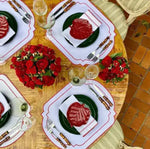 Imperial Crimson Placemats four-place table overhead — white mats with crimson bead-dot border, green plates and red flower decor