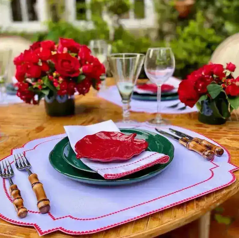Imperial Crimson Placemats outdoor setting — pale white mat with crimson bead-dot scalloped border, green plate and red roses