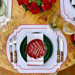 Imperial Crimson Placemats overhead — white rectangular mat with crimson bead-dot scalloped border, green plate and red rose decor