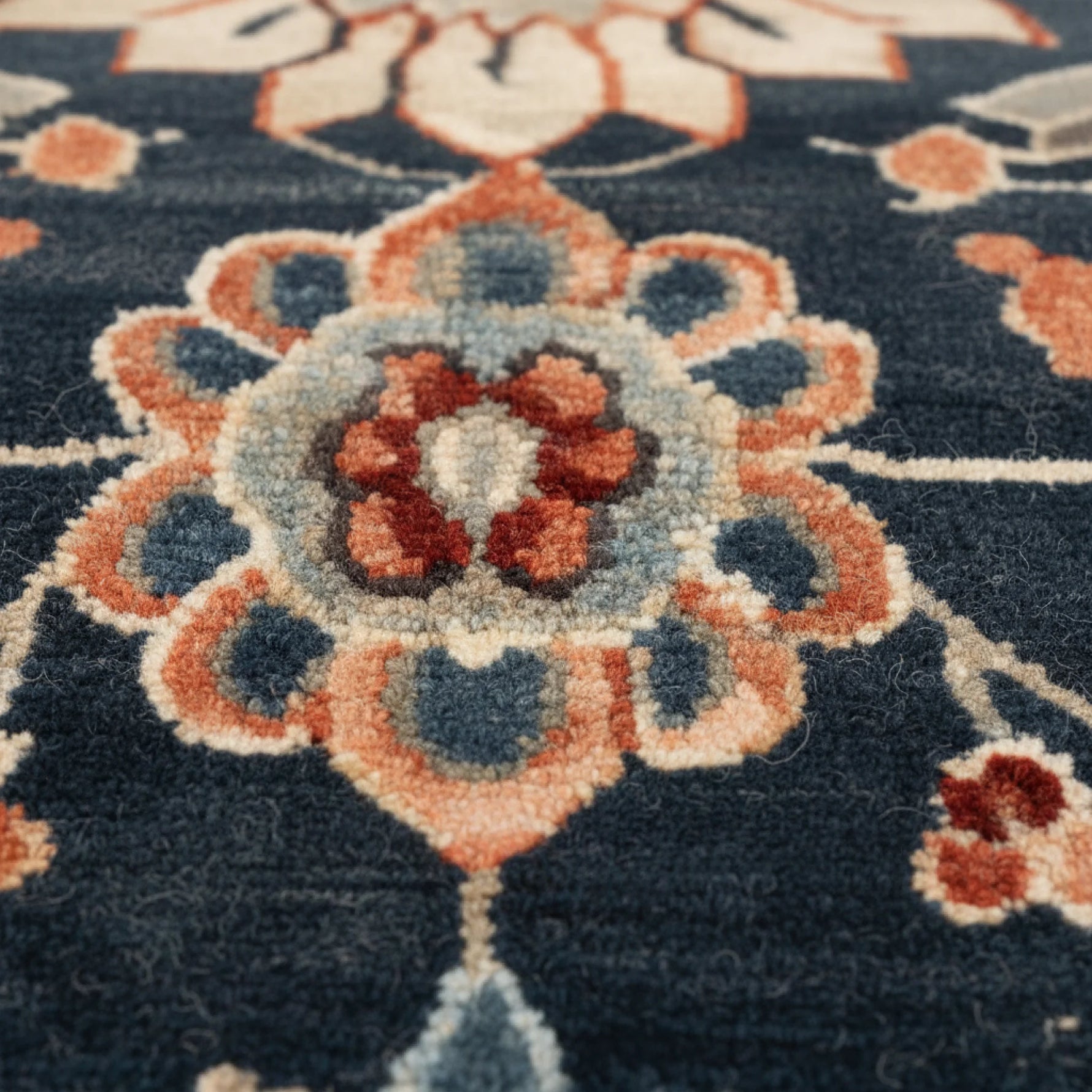 Close-up of a patterned rug with blue, orange, and white colors.