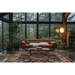 A beautifully designed living room features a luxurious Imperial Jewel Hand Knotted Area Rug with intricate floral patterns, perfect for adding a vintage touch. The square area rug complements the elegant brown leather sofa and modern decor, making it ideal for both living room and dining room settings. Surrounded by lush green plants and large windows, this Persian-inspired wool rug enhances the cozy ambiance with its rich colors.